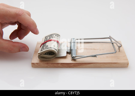 Male hand taking rolled up dollar bills from mousetrap