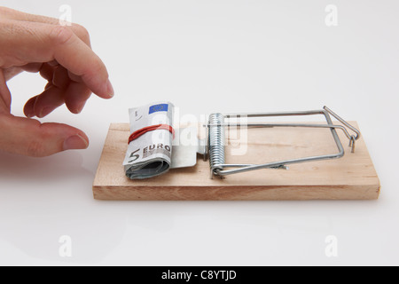 Male hand taking rolled up euro bills from mousetrap