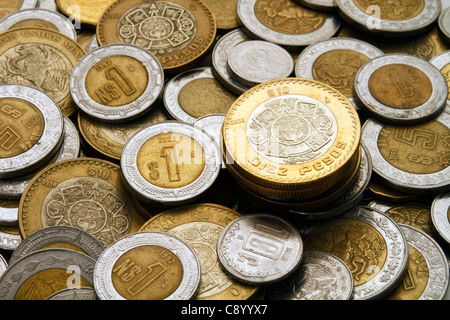 A modern ten Mexican Pesos coin stacked on a pile of other modern Mexican Peso Dollar and cent coins. Stock Photo
