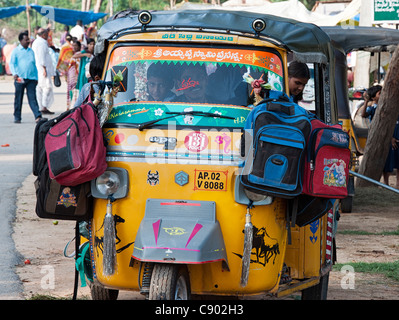 Indian auto rickshaw full of school children with their bags hanging on the wing . Andhra Pradesh, India Stock Photo