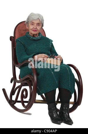 Image of an old woman sitting on a rocker with a closed book in her lap. Stock Photo