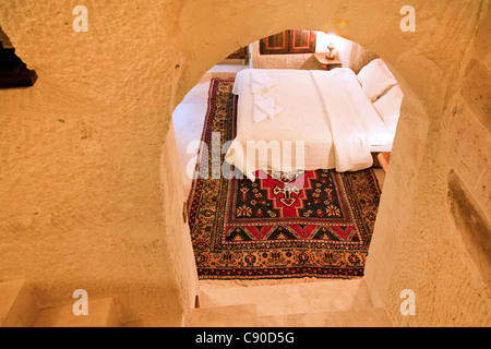 renovated bedroom in a limestone cave residence viewed through an archway, double bed with white linen, furnishings Stock Photo