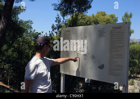 Visitor to Epidavros in Greece looking and pointing at layout plan of the site Stock Photo