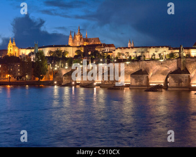 Prague Castle and St Vitus Cathedral illuminated at dusk, with Charles Bridge and Vitava River Stock Photo