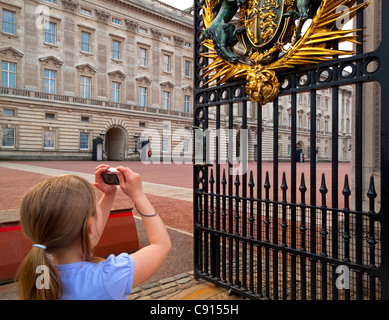 Young girl tourist photographing outside the gates of Buckingham Palace Westminster London England UK Stock Photo