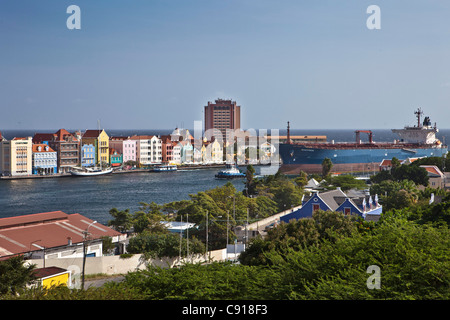 Curacao, Caribbean island, Willemstad. Historic houses on waterfront. Dusk. Oil tanker passing Sint Annabaai. Stock Photo