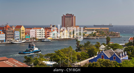 Curacao, Caribbean island, Willemstad. Punda quarter. Historic houses on waterfront. Towboat passing Sint Annabaai. Stock Photo