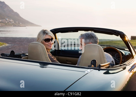 Couple in convertible admiring coastline Stock Photo