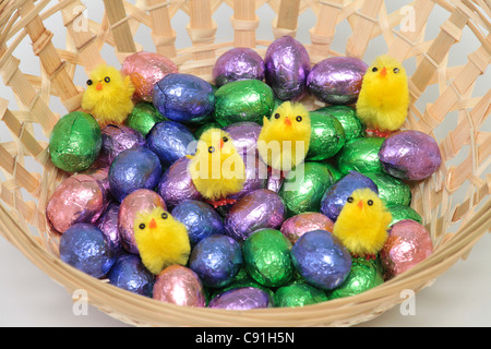 Little fake chickens on chocolate easter eggs in a basket Stock Photo