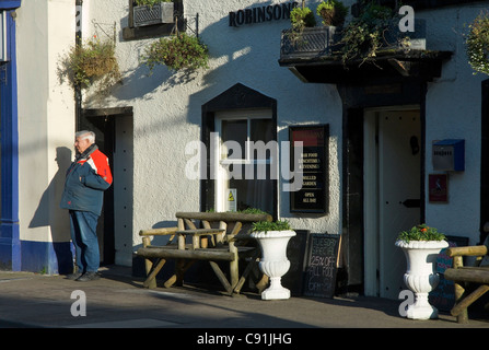 Man waiting outside the Rose & Crown pub, King Street, Ulverston, Cumbria, England UK Stock Photo