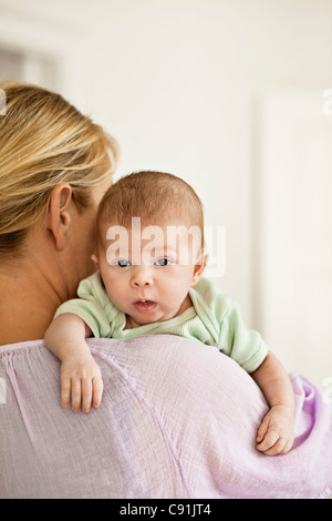 Mother cradling infant on shoulder Stock Photo