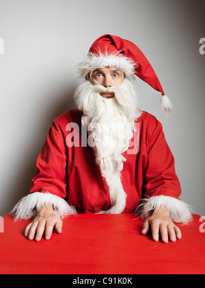 Man in Santa Claus suit sitting at table Stock Photo