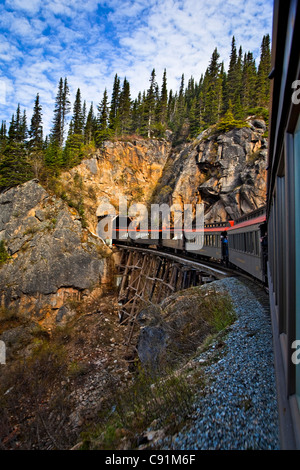 White Pass & Yukon train crosses a trestle and enters a tunnel, Skagway, Southeast Alaska, Summer Stock Photo