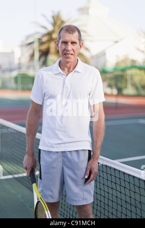 Older man with tennis racket on court Stock Photo