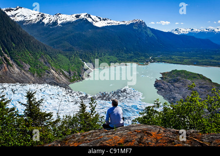 A male hiker looking down onto Mendenhall Glacier and Mendenhall Lake from West Glacier Trail, Juneau, Southeast Alaska, Summer Stock Photo