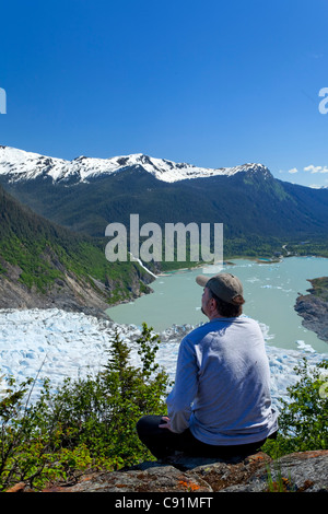 A male hiker looking down onto Mendenhall Glacier and Mendenhall Lake from West Glacier Trail, Juneau, Southeast Alaska, Summer Stock Photo