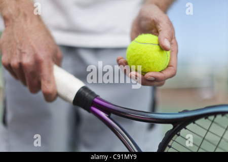 Older man holding tennis ball and racket Stock Photo