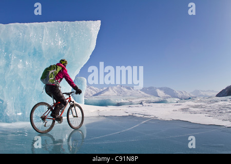 Woman Fat Tire mountain biking on ice at the Knik Glacier, Chugach Mountains, Southcentral Alaska, Winter Stock Photo