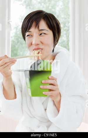 Woman in bathrobe eating Chinese food Stock Photo