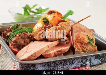 Roast pork, stuffed pepper and tomatoes and kebabs in a baking pan Stock Photo