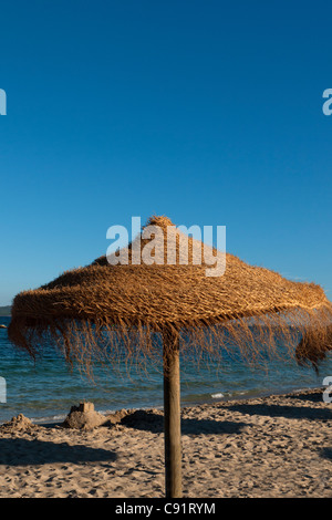Wicker parasol on sunny summer sandy beach, Puerto de Pollenca, Mallorca, Spain Stock Photo