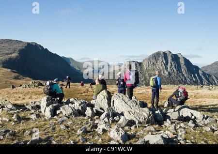 Group of Ramblers resting on ascent of Y Foel Goch with Tryfan and Glyder Fach Bristly ridge in Snowdonia National Park UK Stock Photo