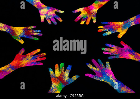 Coloured powder hand prints in a circular pattern on black Stock Photo