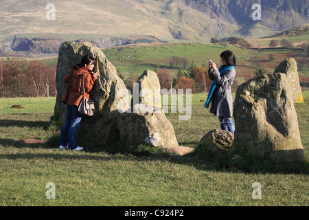 Two young women of east Asian appearance taking a photograph at Castlerigg Stone Circle,near Keswick, north west England, UK Stock Photo