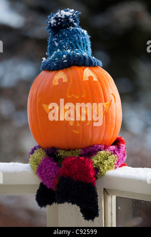 Close up of a carved pumpkin with the word Alaska carved as teeth and sitting on deck railing , Alaska Stock Photo