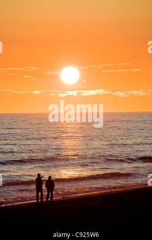 A couple walks the Homer Spit beach at sunset along Kachemak Bay, Kenai Peninsula, Southcentral Alaska, Summer