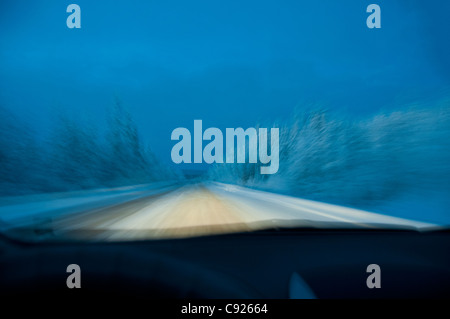 Driver's perspective of driving in the evening on a remote snowcovered road in Kluane National Park, Yukon Territory, Canada Stock Photo