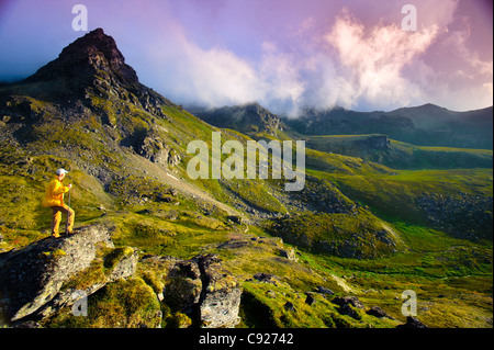 Man hiking near Hatcher Pass in the Talkeetna Mountains with Bald Ridge in the background, Southcentral Alaska, Summer Stock Photo