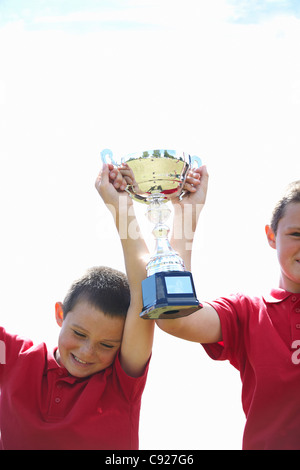 Boys cheering with trophy outdoors Stock Photo