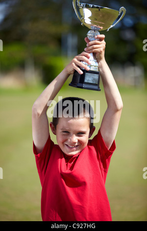 Boy cheering with trophy outdoors Stock Photo