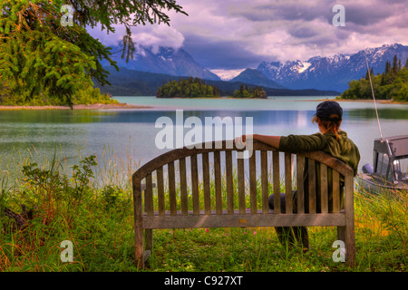 Woman enjoying the view of Lake Clark from an island bench, Lake Clark National Park, Southcentral Alaska, Summer, HDR