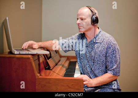 Man playing music with piano and laptop Stock Photo
