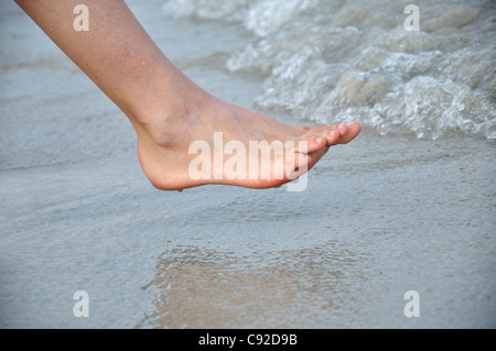 Young woman walking barefoot on beach, close-up Stock Photo