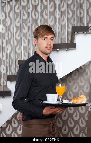 Waiter holding breakfast tray in cafe Stock Photo