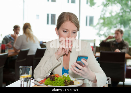 Businesswoman using cell phone at lunch Stock Photo