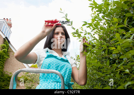 Woman pruning plants in backyard Stock Photo