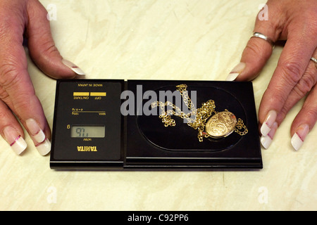 female jeweler weighing scrap gold on a set of electronic scales Stock Photo