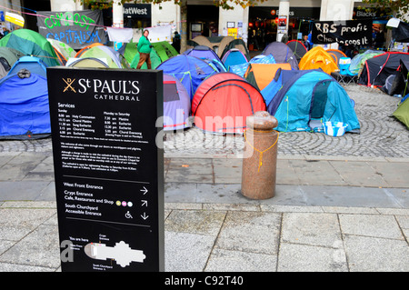 St Pauls cathedral information panel with anti capitalist protesters tents and Stock Exchange entrance beyond City of London England UK Stock Photo