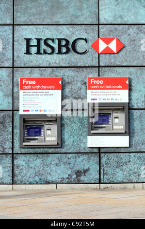 Two HSBC bank ATM cash machines free withdraw cash from a hole in wall of bank premises below bank sign and logo in City of London England UK Stock Photo