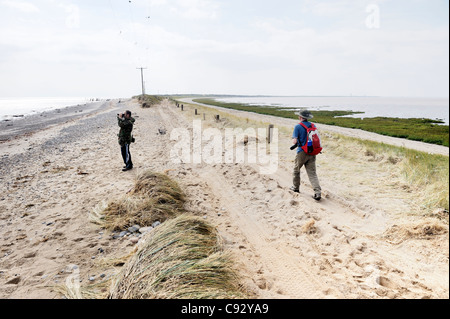 Sea storm coastal erosion at Spurn Head, Yorkshire east coast England. Bird watchers on damaged narrowest point of sand spit Stock Photo