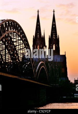 Koln Cologne Cathedral silhouetted against evening sky beyond the Hohenzollern railway bridge across the River Rhine, Germany Stock Photo