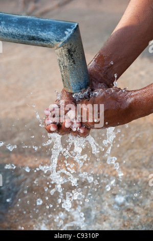 Indian man washing his hands at a water pump in the indian countryside Stock Photo