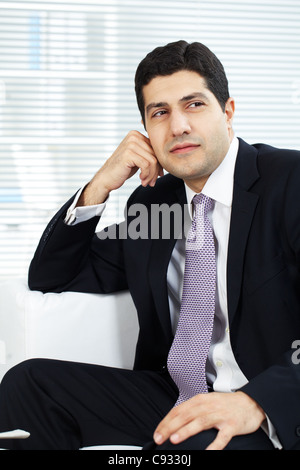 Portrait of attractive businessman in suit sitting in office Stock Photo