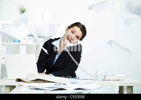 Portrait of busy office worker typing and speaking on the phone Stock Photo
