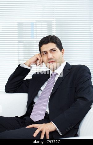 Portrait of attractive businessman in suit sitting in office Stock Photo