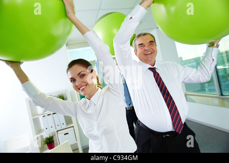 Portrait of joyful business partners playing with big balls in office Stock Photo
